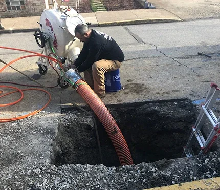 A concrete drainage channel embedded in a dirt roadside, featuring a cylindrical pipe for water flow.